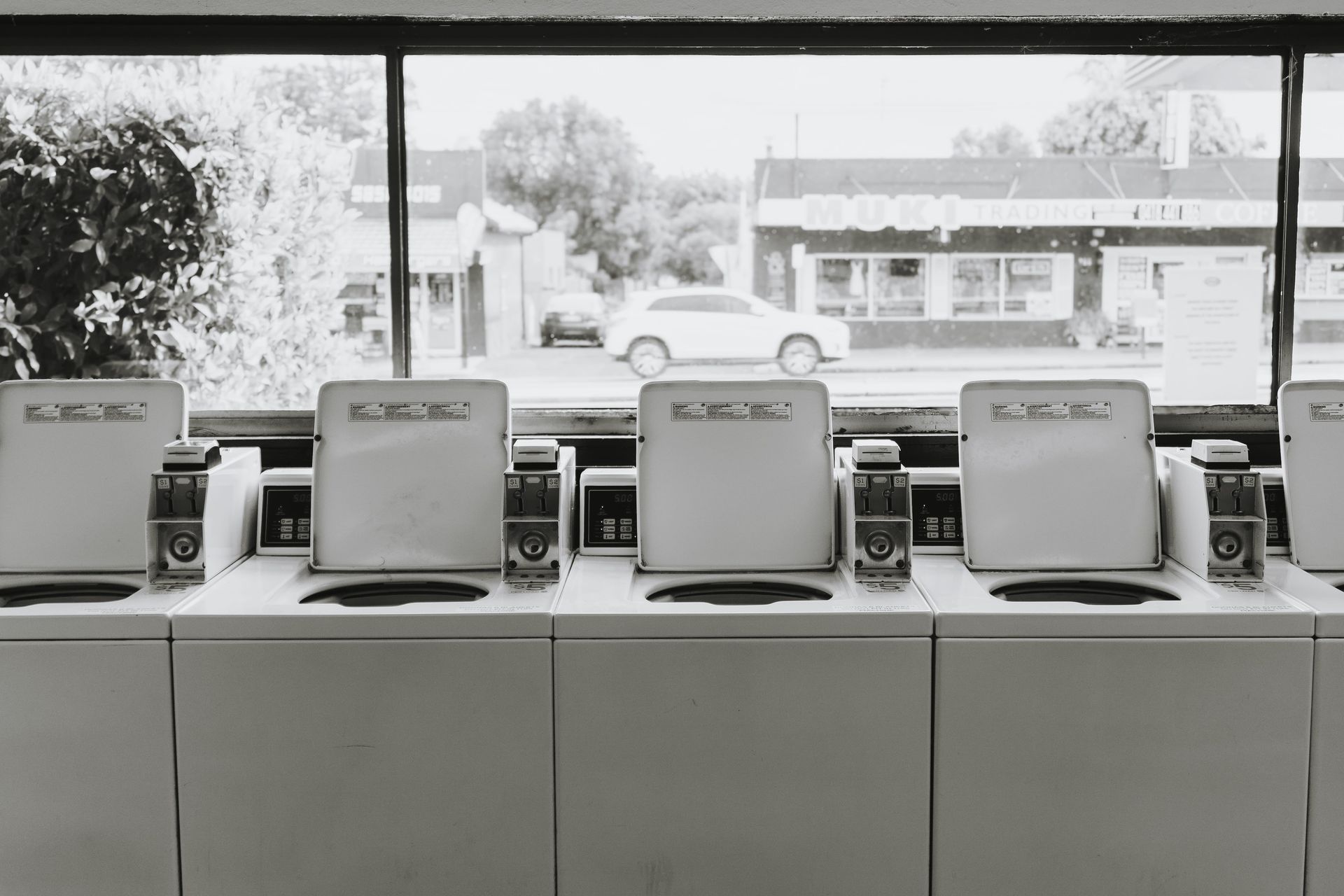 A black and white photo of a row of washing machines in a laundromat — The Wash House& Laundrette in Dubbo, NSW