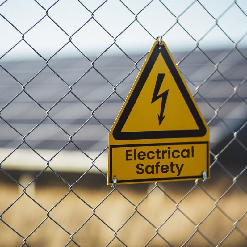 A sign on a chain link fence warns of electrical safety