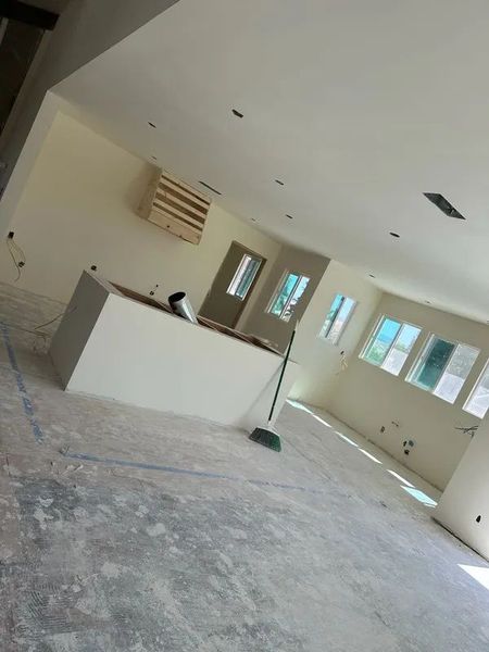 Interior view of a room under construction with an island, windows, and a broom.