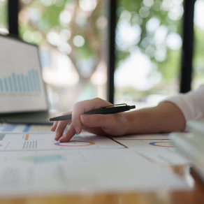 Uma pessoa está sentada à mesa com uma caneta na mão.