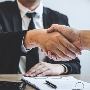 Um homem de terno e gravata aperta a mão de outro homem