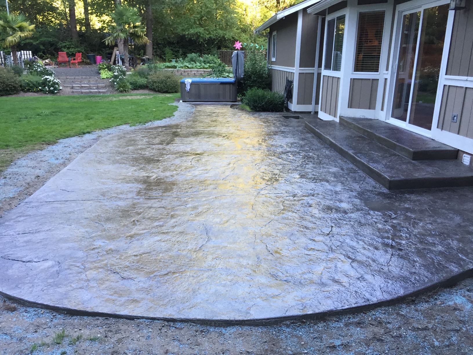 Concrete patio beside screened porch in a backyard with lawn and garden beds
