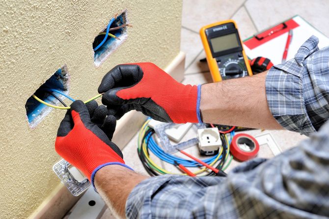 A man wearing red gloves is working on electrical wires