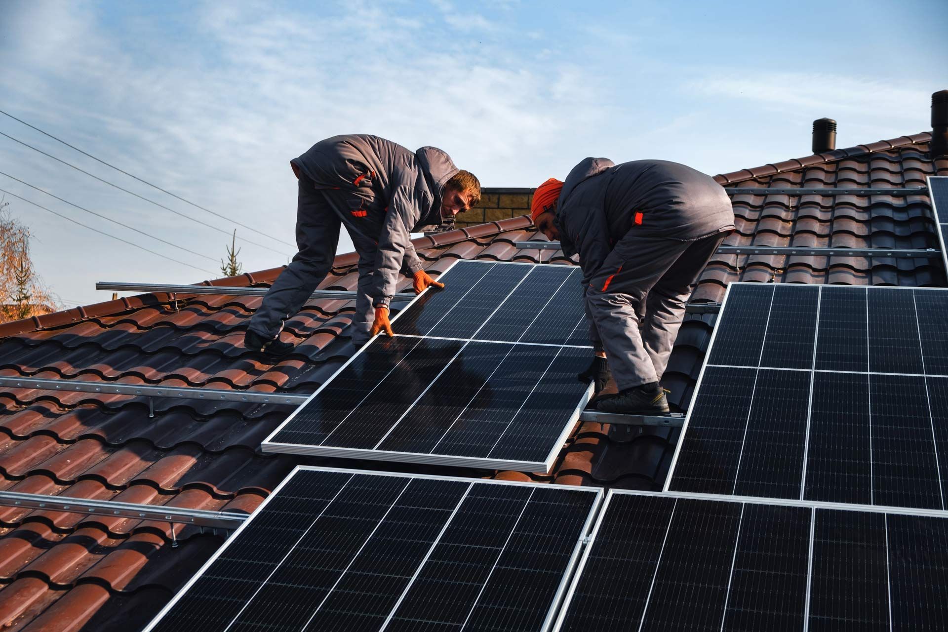 Two men are installing solar panels on the roof of a house
