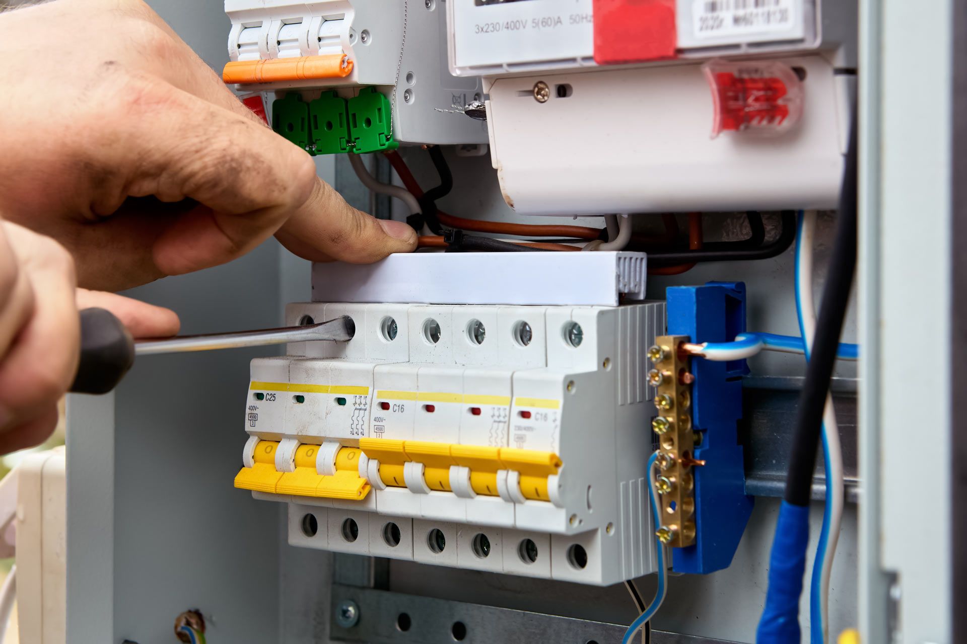 A person is working on an electrical box with a screwdriver