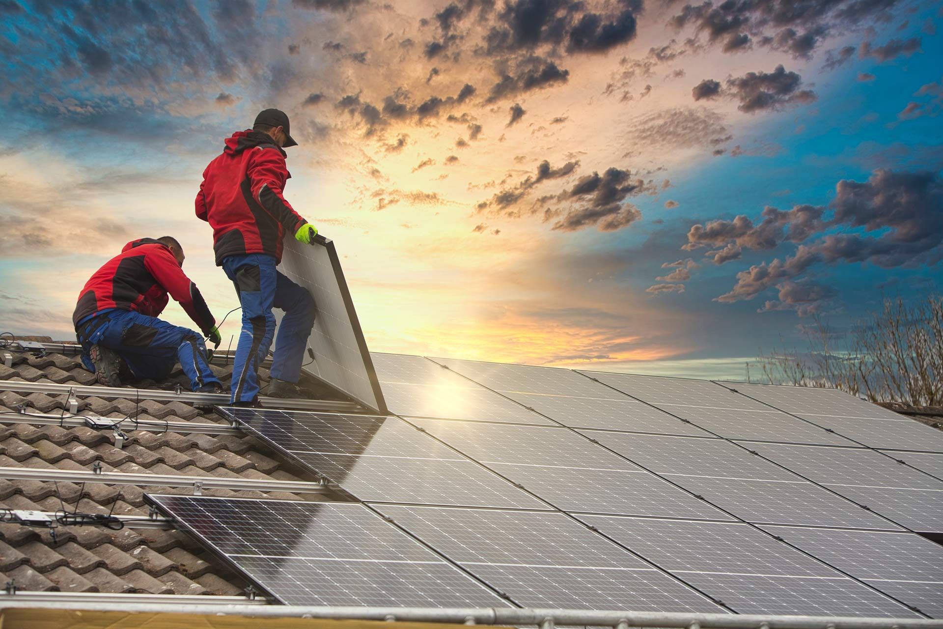 Two men are installing solar panels on the roof of a house