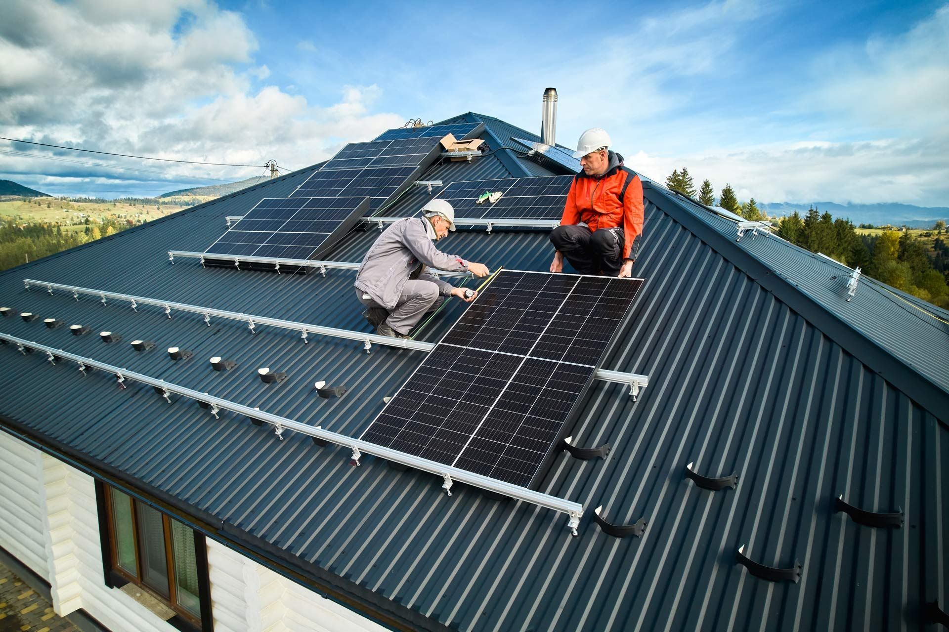 Two men are installing solar panels on the roof of a house
