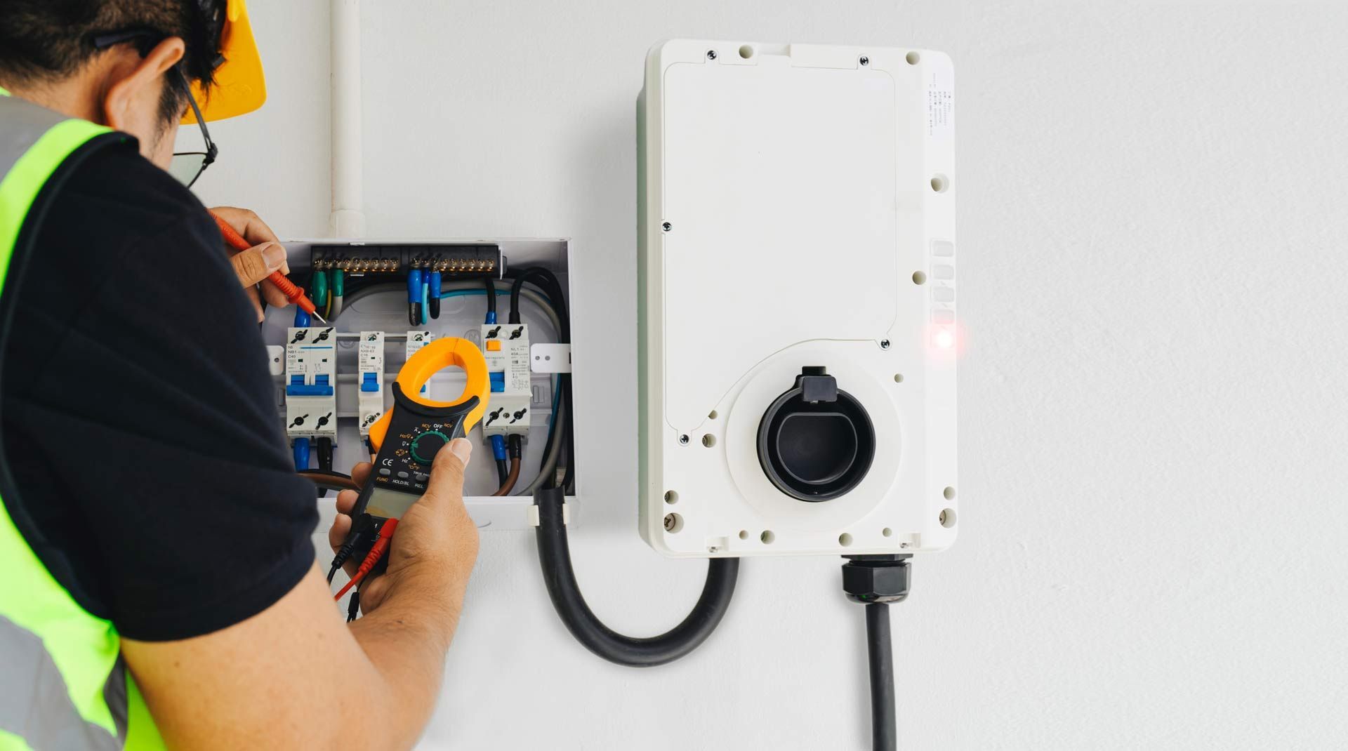A man is working on an electric car charger on a wall