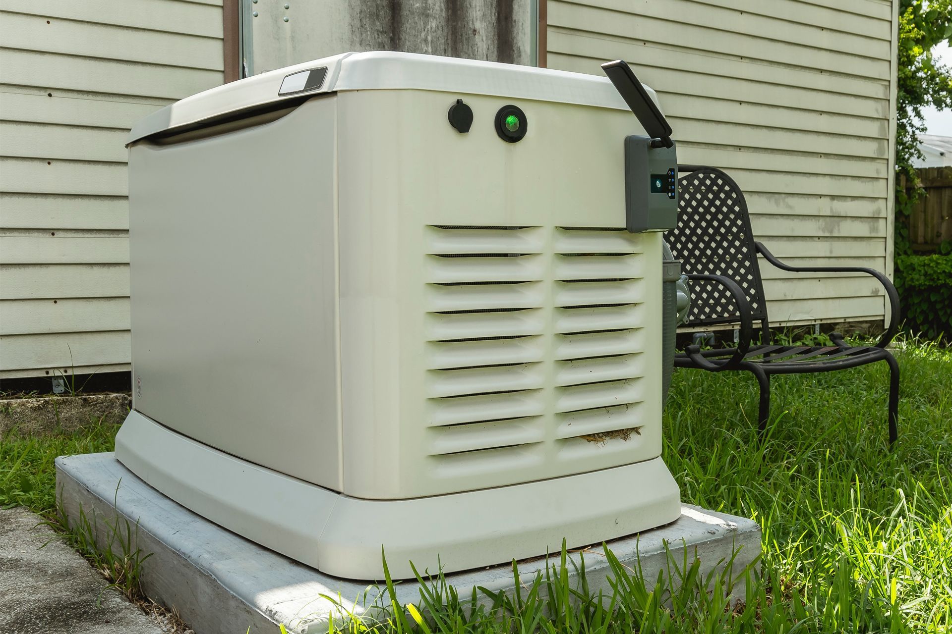 A generator is sitting in the grass in front of a house