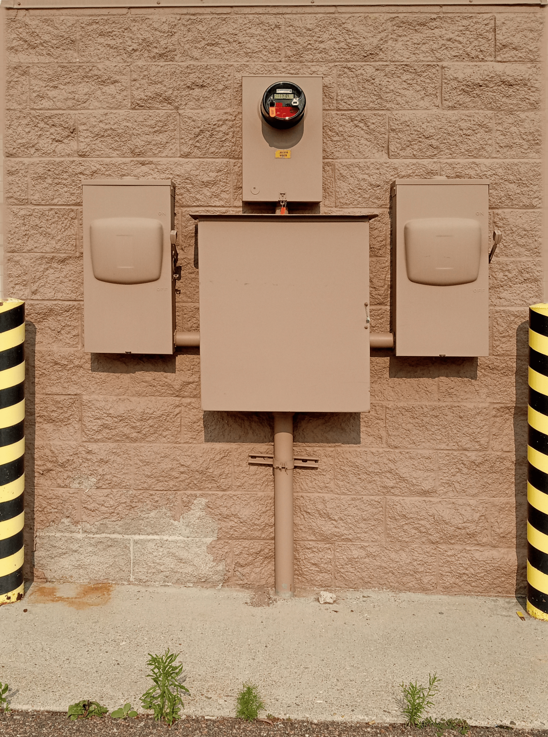 Wall-mounted electrical boxes on a tan stucco wall, framed by black-and-yellow striped posts.