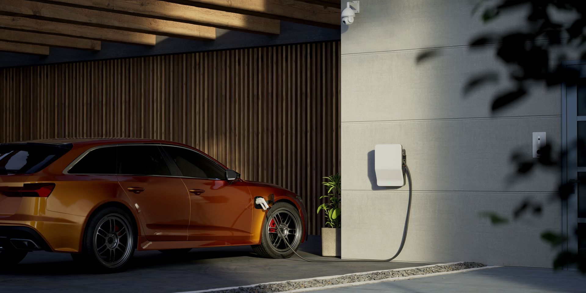 Orange sports car parked in a modern garage beside a wall-mounted charging cable