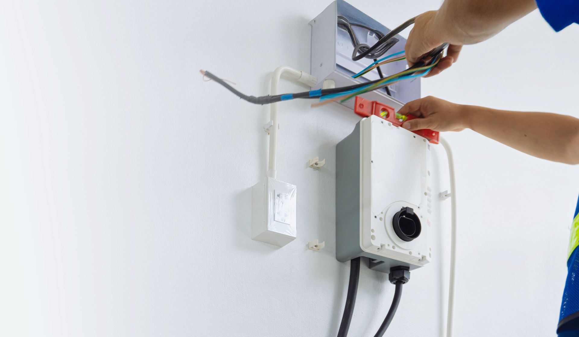 Electrician connecting wires to a wall-mounted boiler control panel indoors