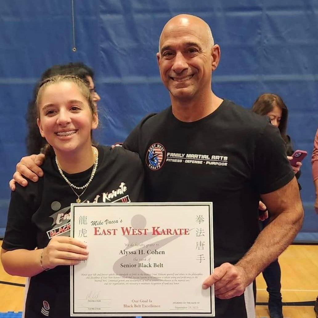 a man and a girl holding a certificate that says east west karate