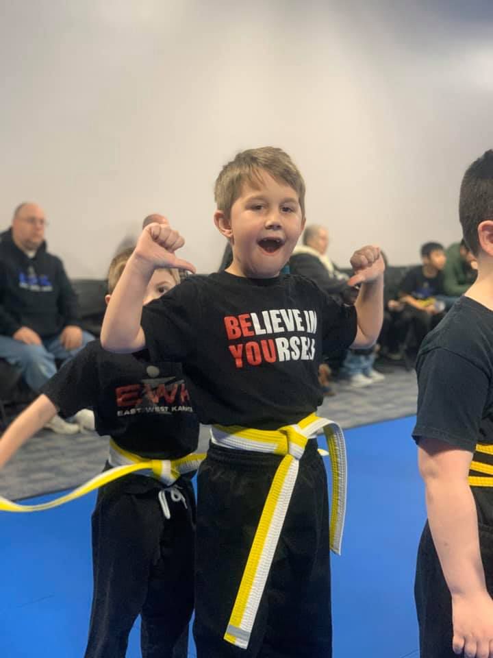 a young boy wearing a black shirt that says believe in yourself