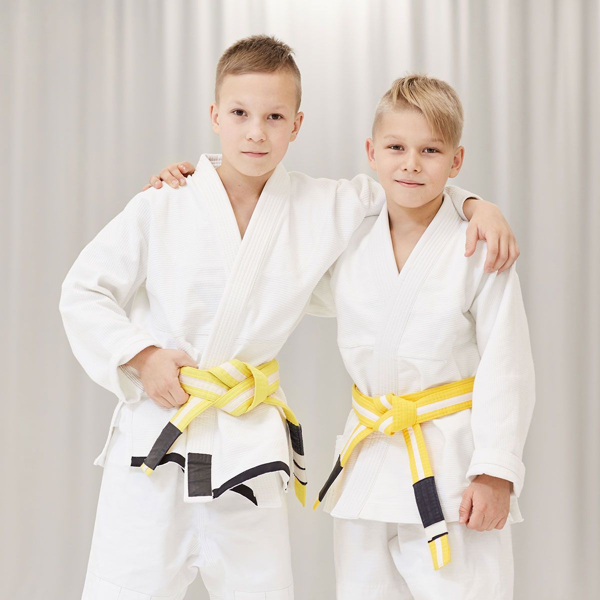 two young boys wearing white karate uniforms with yellow belts