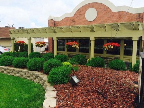 A brick building with a pergola and flowers in front of it Harvest Moon Cafe Ypsilanti MI