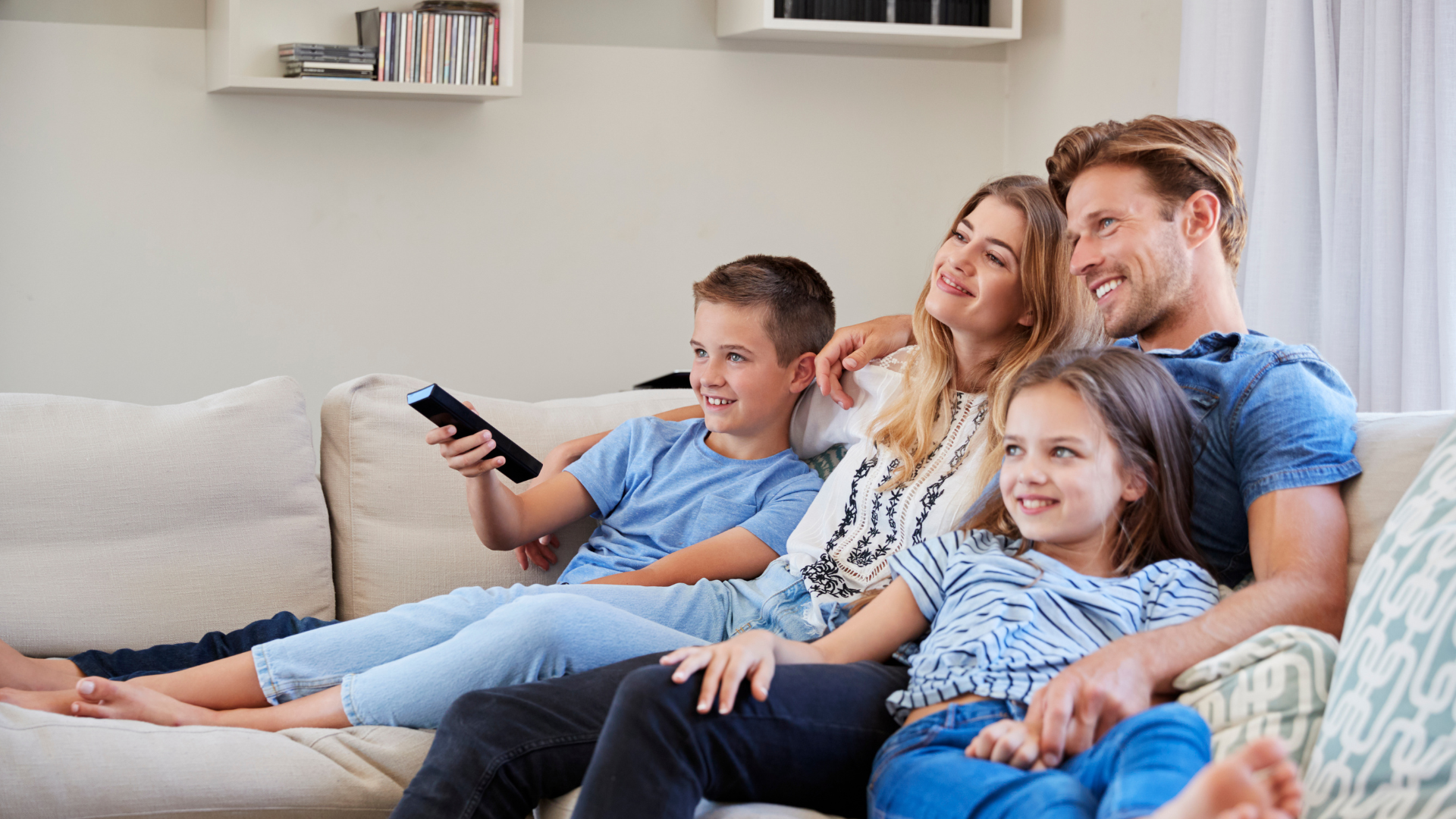 A family is sitting on a couch watching tv