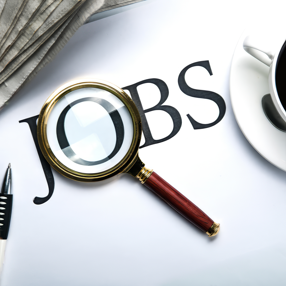 A magnifying glass is on a piece of paper that says jobs