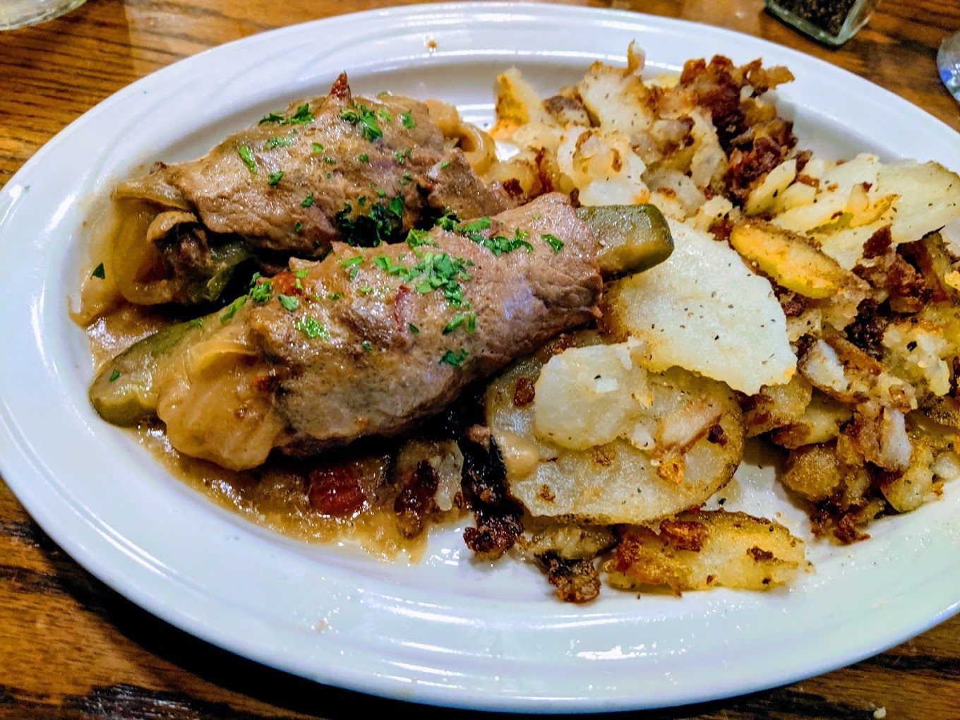 A white plate topped with meat and potatoes on a wooden table Metzgers Germnan Food Ann Arbor MI