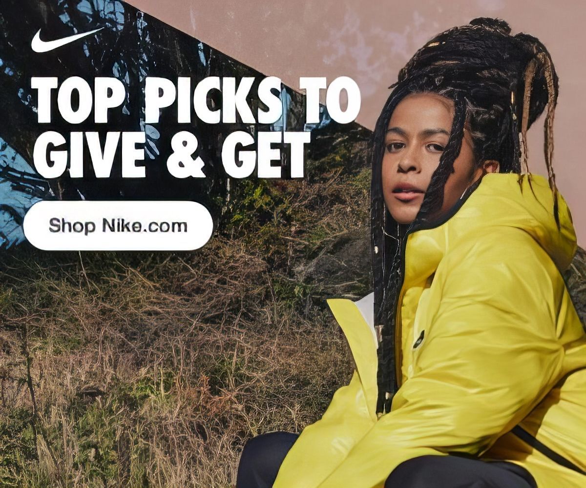 A woman wearing a yellow nike jacket is sitting in a field