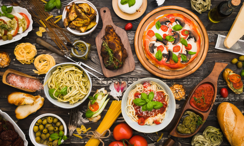 A table topped with plates of food including pasta salad and pizza Ypsilanti MI Restaurants