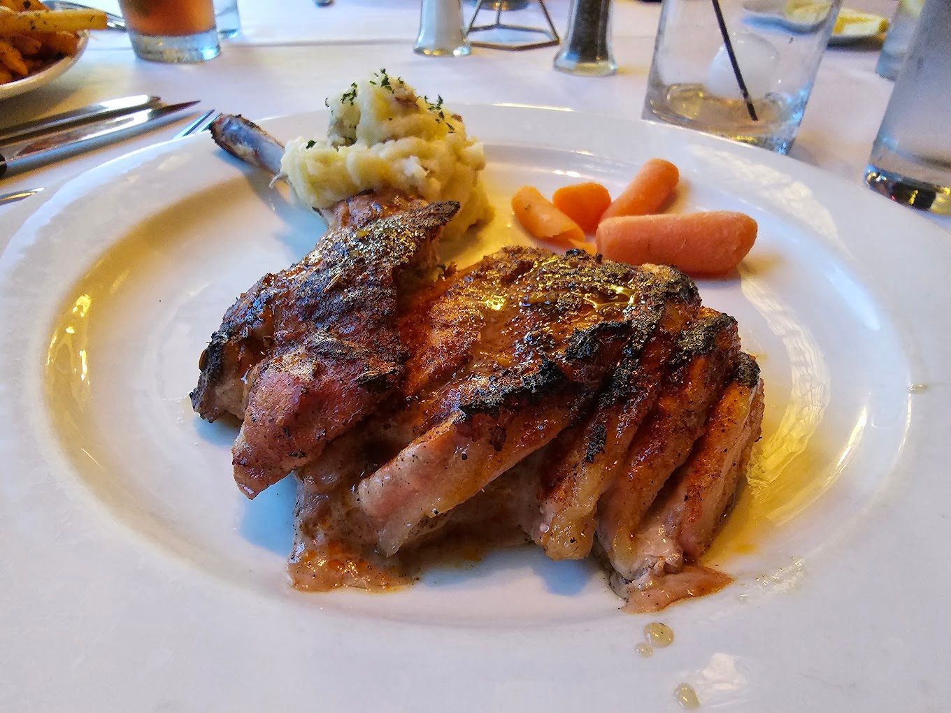 A white plate topped with meat and carrots on a table The West End Grill Ann Arbor