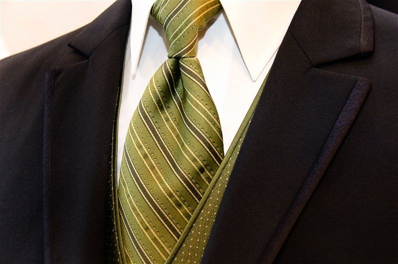 A man wearing a black suit and green tie