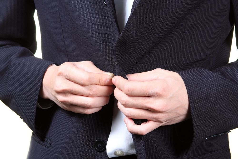 A man in a suit is adjusting his jacket