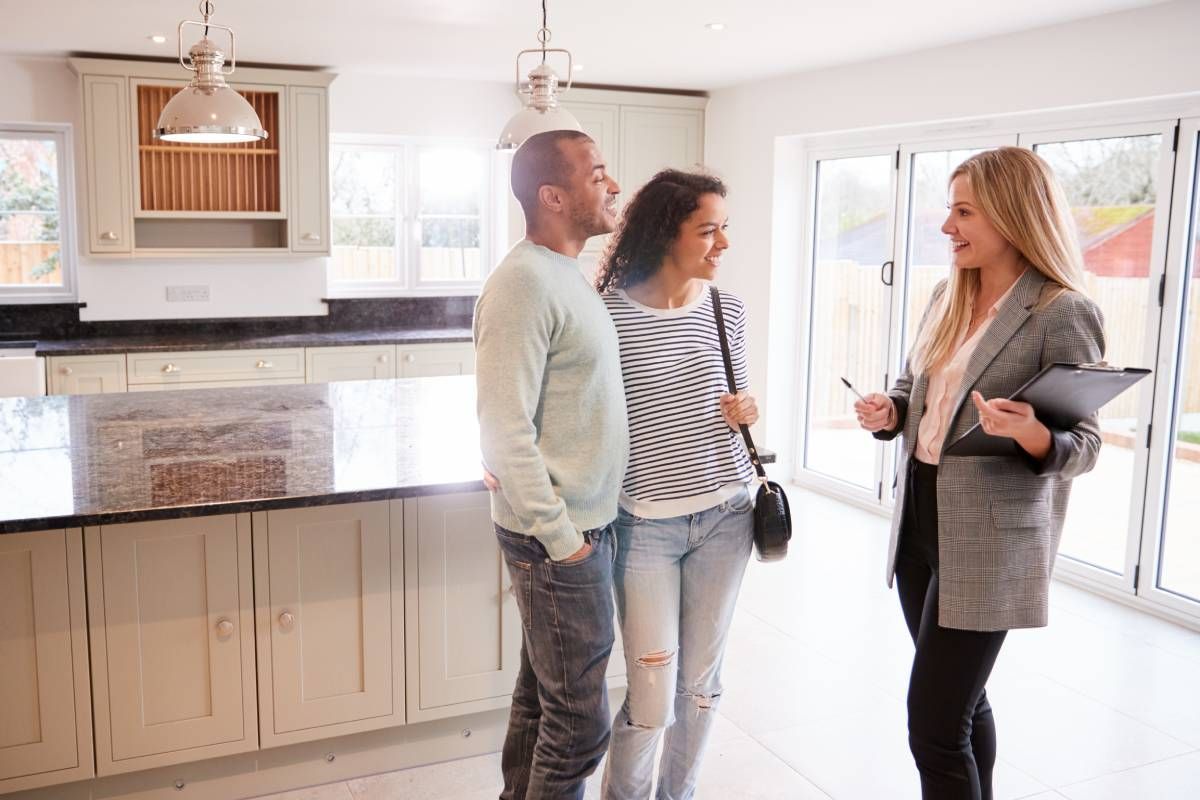 A realtor talking to two interested clients about a home at HomeServices Real Estate Academy near Kentucky, Indiana, and Ohio