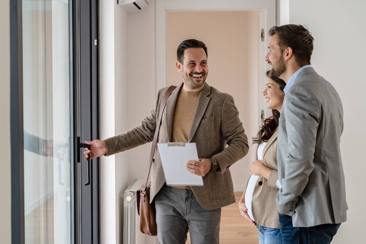 A real estate agent showing a property to a young married couple at HomeServices Real Estate Academy near Lexington, KY