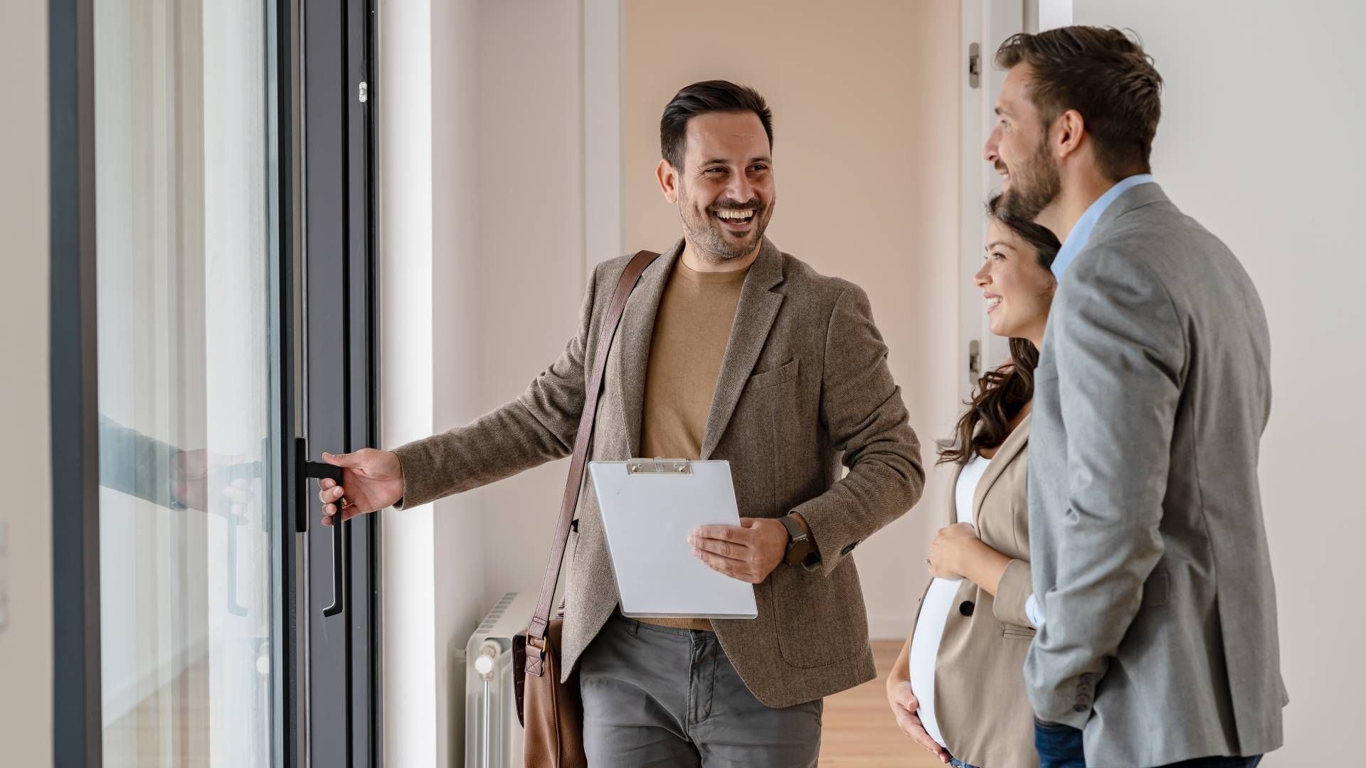 A real estate agent showing a property to a young married couple at HomeServices Real Estate Academy