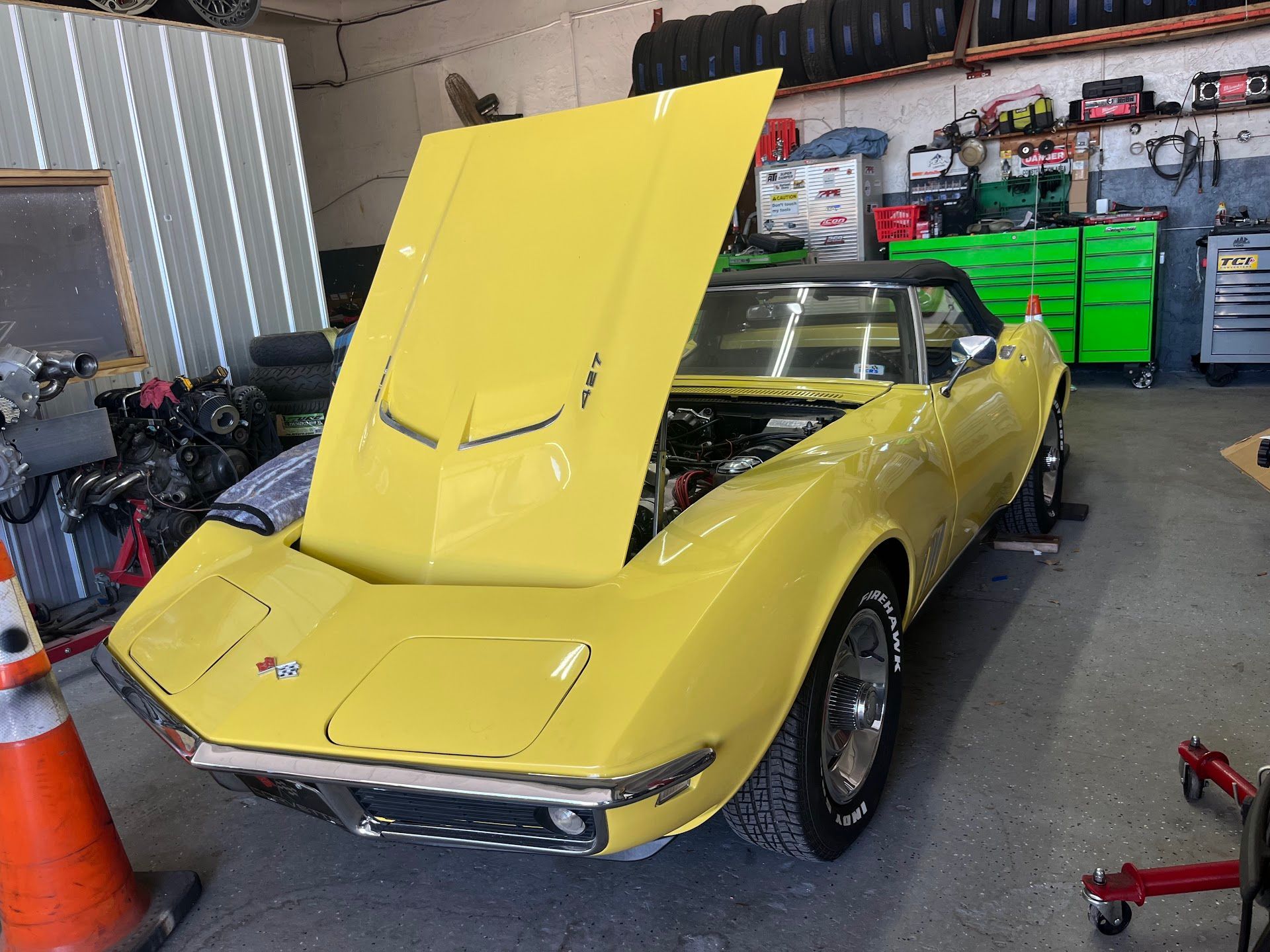 Yellow convertible Corvette with open hood in a garage. | East Coast Motorworks