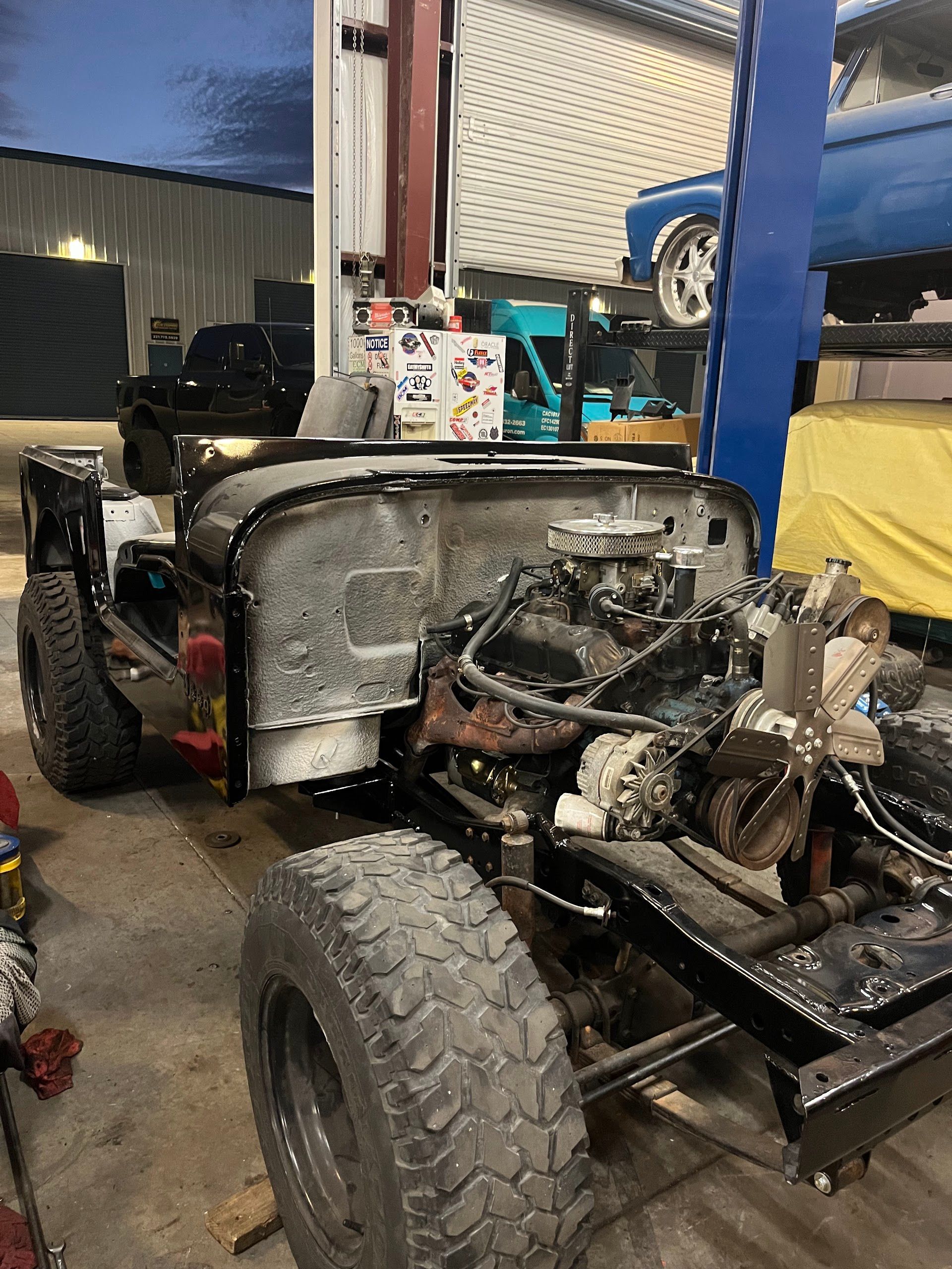 Jeep frame undergoing restoration, engine visible, inside a garage. | East Coast Motorworks