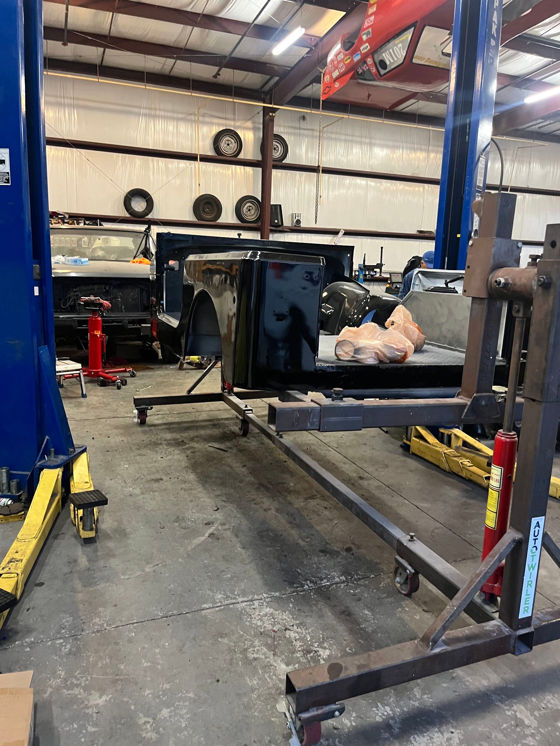 Car repair shop interior with vehicle body on a cart and lift equipment. | East Coast Motorworks