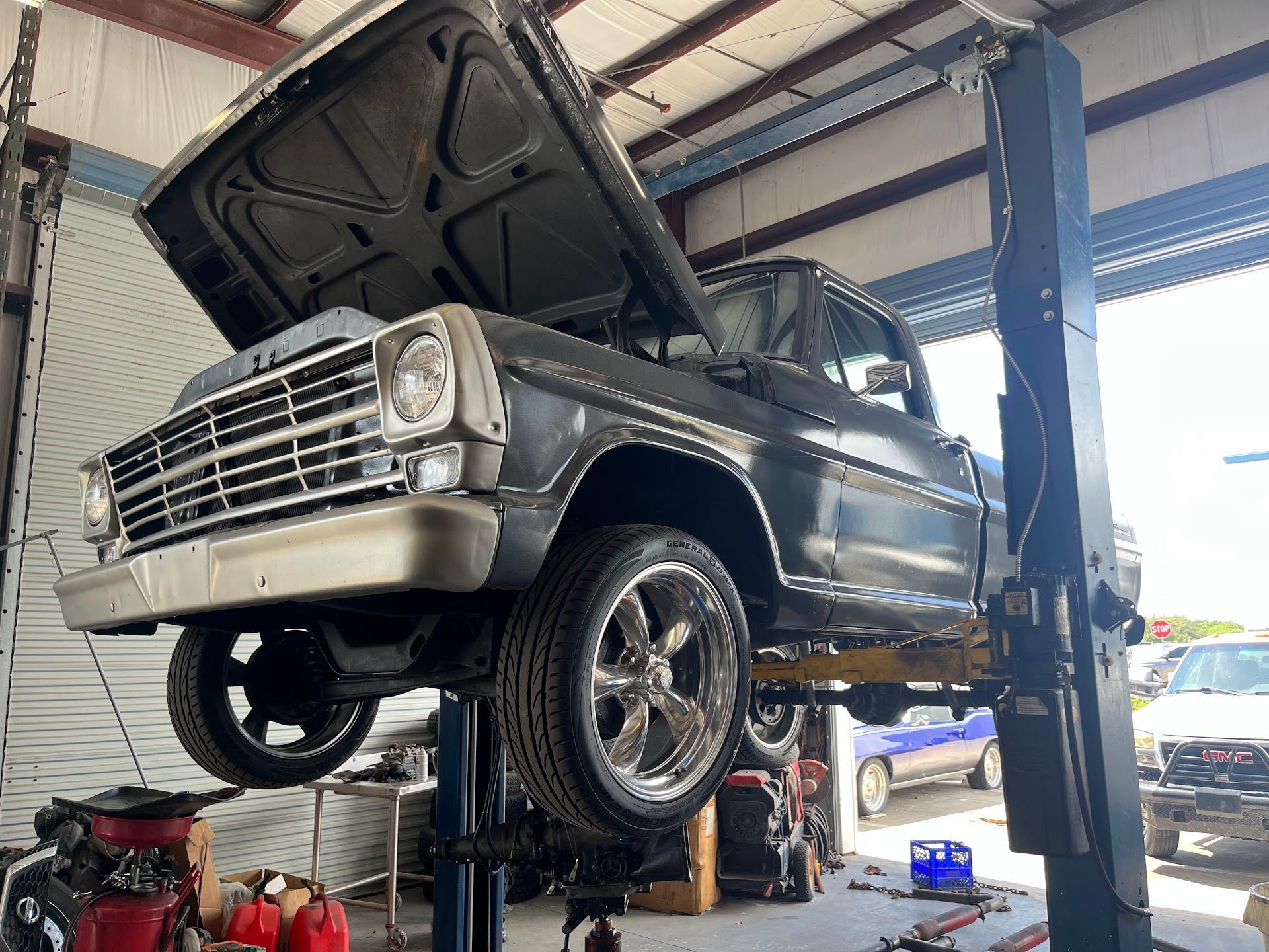Classic gray Ford pickup truck raised on a lift inside a repair shop. | East Coast Motorworks