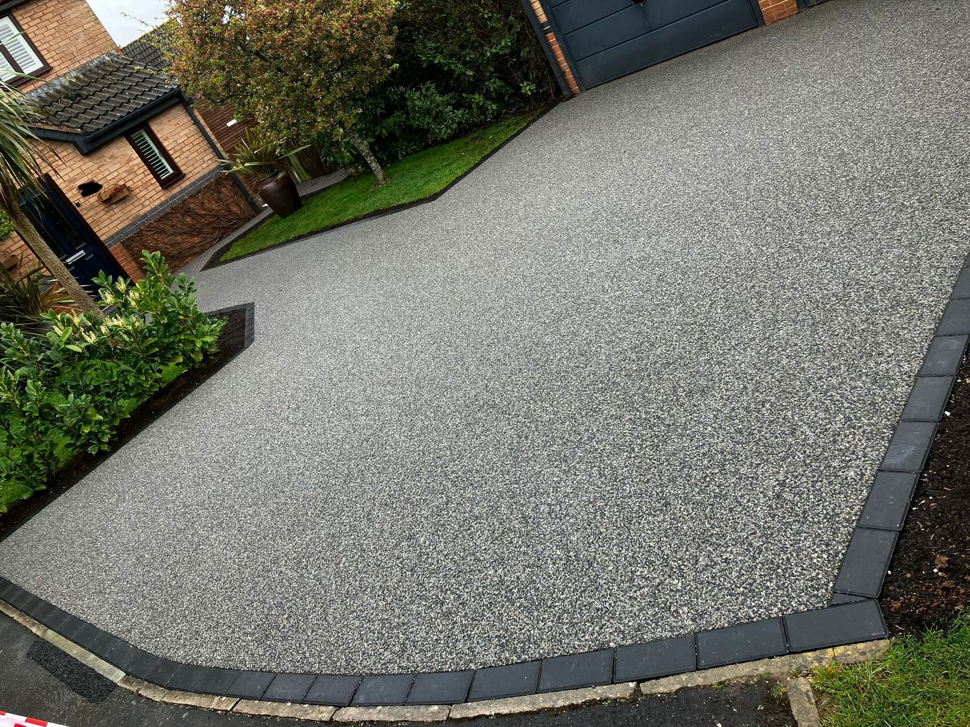 Newly installed grey resin driveway with a dark grey block paving border. 