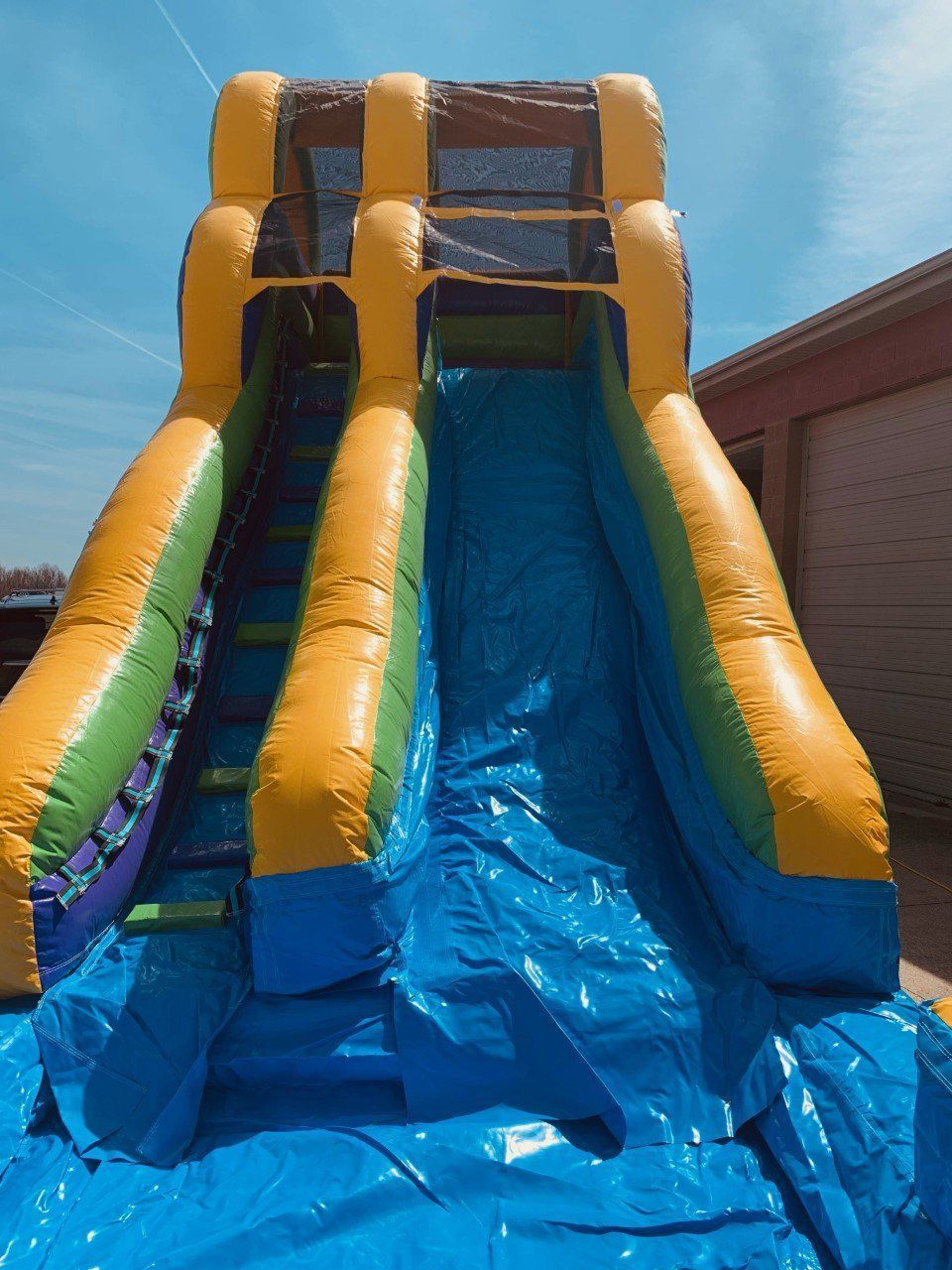 A large inflatable water slide is sitting on top of a blue tarp.