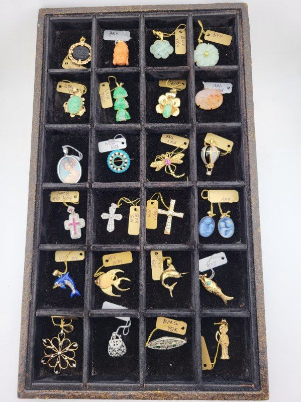 Jewelry display case with pendants and earrings of various shapes and colors against a black backdrop.