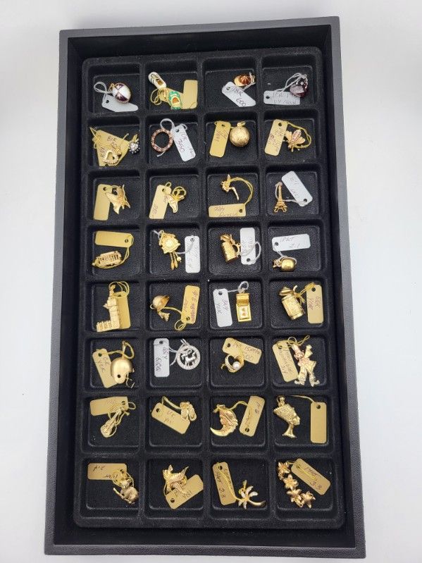 Black tray filled with gold and silver charms, displayed on a white background.