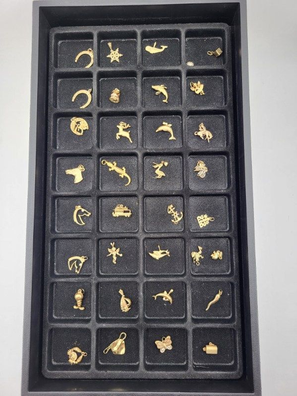 Tray of gold charms in various shapes, including animals, flowers, and symbols.
