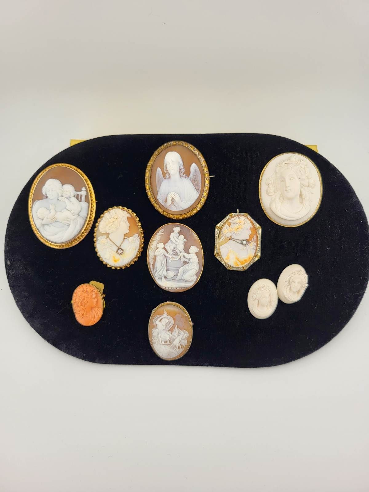 Jewelry display: rings, necklaces, bracelets, earrings with diamonds and red gemstones on red velvet, pink lace, and white cherub statues.