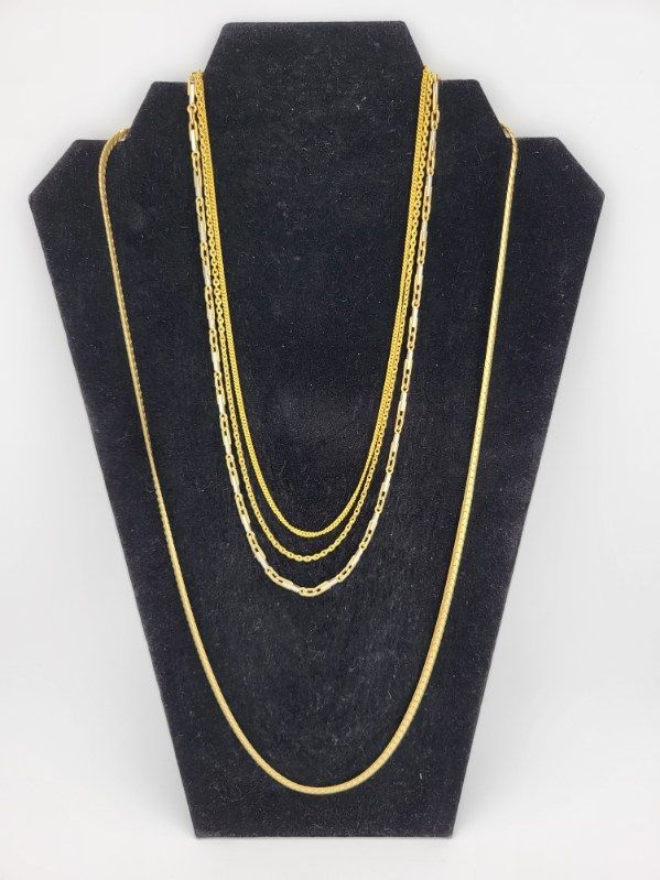 Gold necklaces on a black jewelry display stand.
