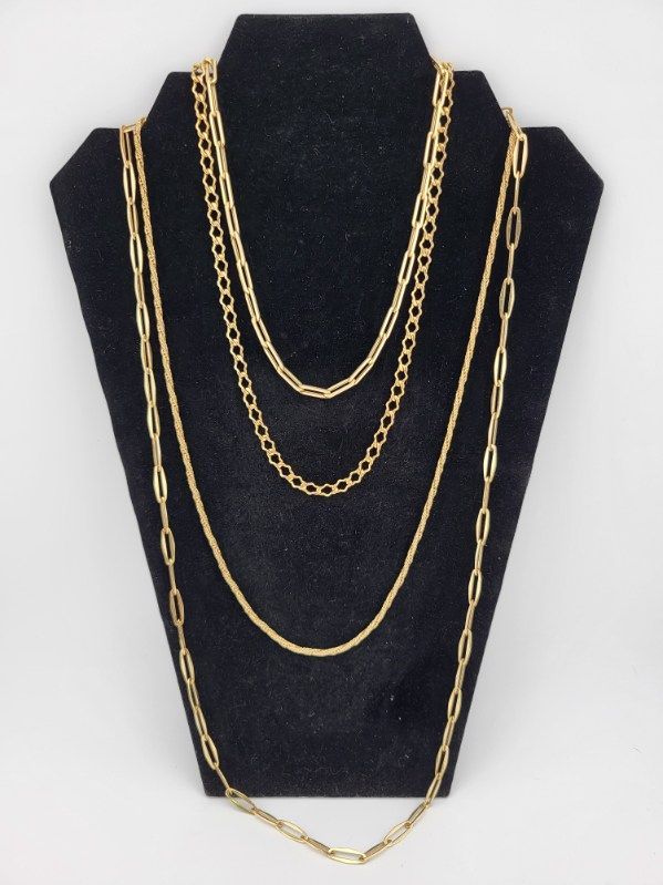 Gold necklaces displayed on a black jewelry stand, various chain styles.