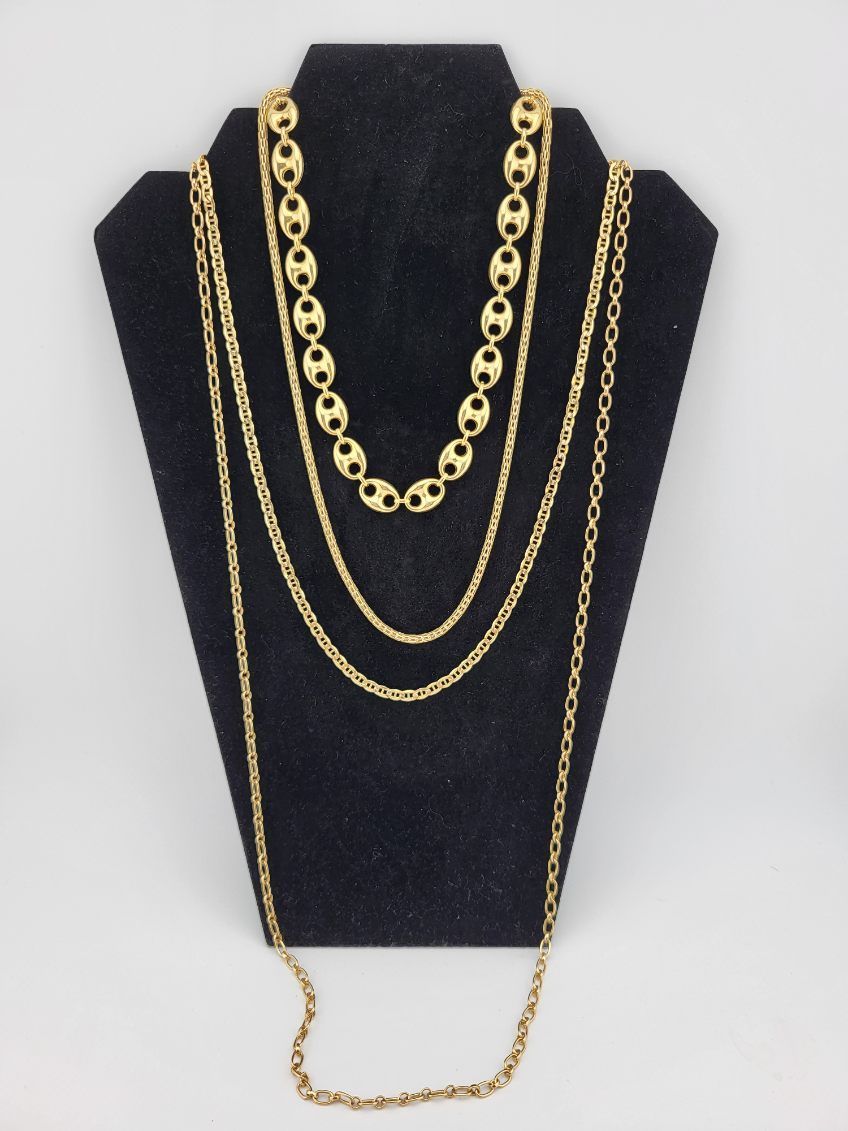 Four gold necklaces on a black display stand against a white background.