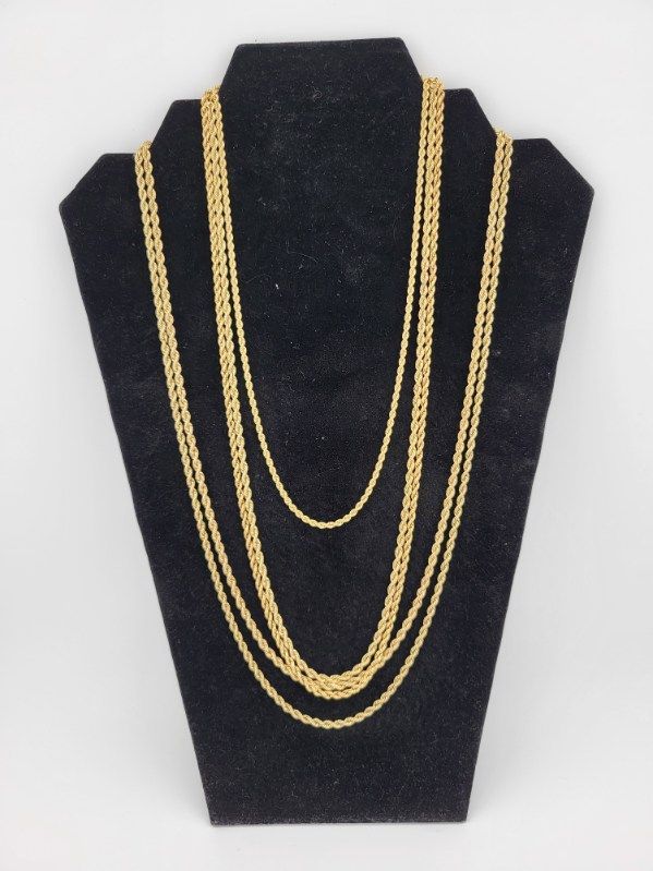 Gold necklaces displayed on a black velvet jewelry stand.