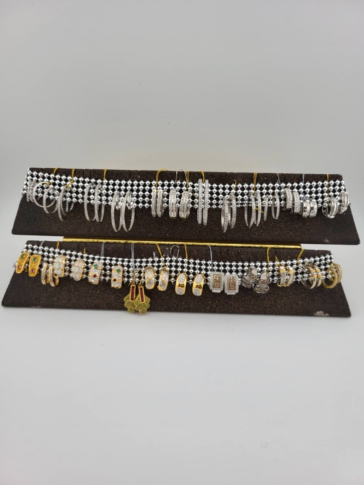 Earrings displayed on two brown velvet platforms with gold hooks, against a white background.