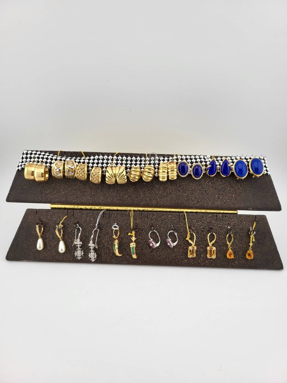 Earrings on two tiered displays, gold, silver, and blue stones. Black and white background.