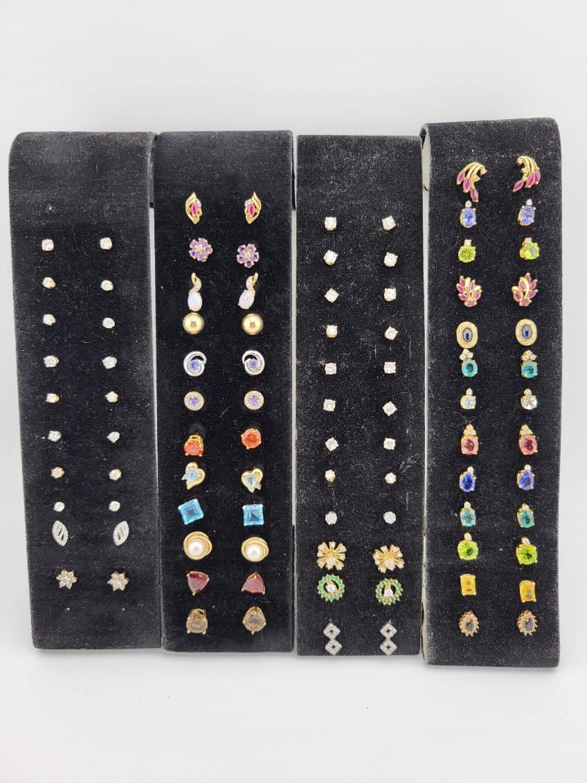 Four black velvet displays showcasing an assortment of stud earrings with various gemstones.