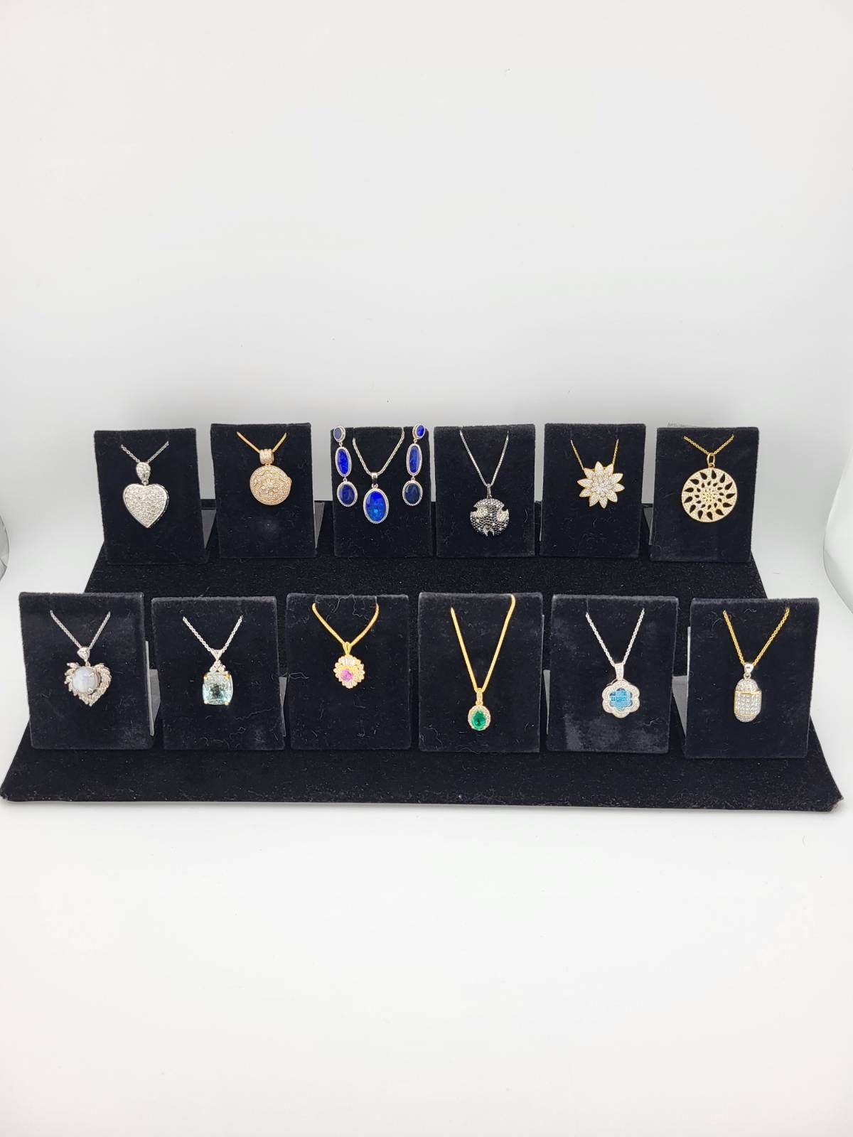 Necklaces with various pendant designs displayed on black stands against a white background.