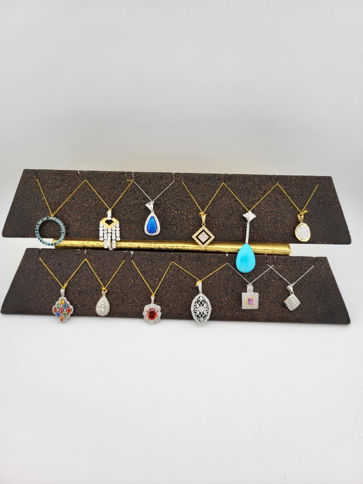 Jewelry display with necklaces featuring various pendant styles and colors arranged on brown platforms.